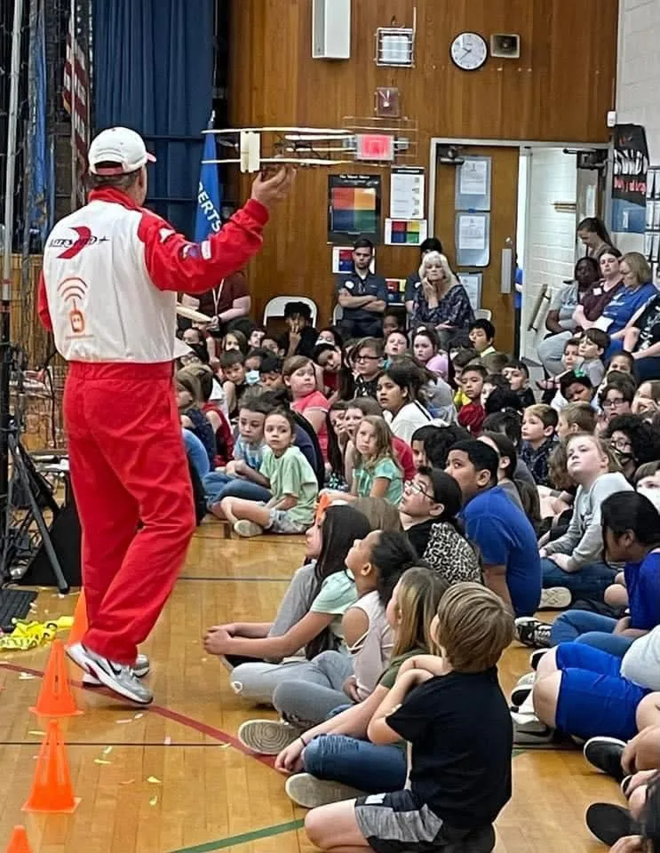 Litespeed Airshow pilot demonstrating a model aircraft to elementary students in a school gym